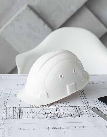 A white construction helmet with blueprint on the table